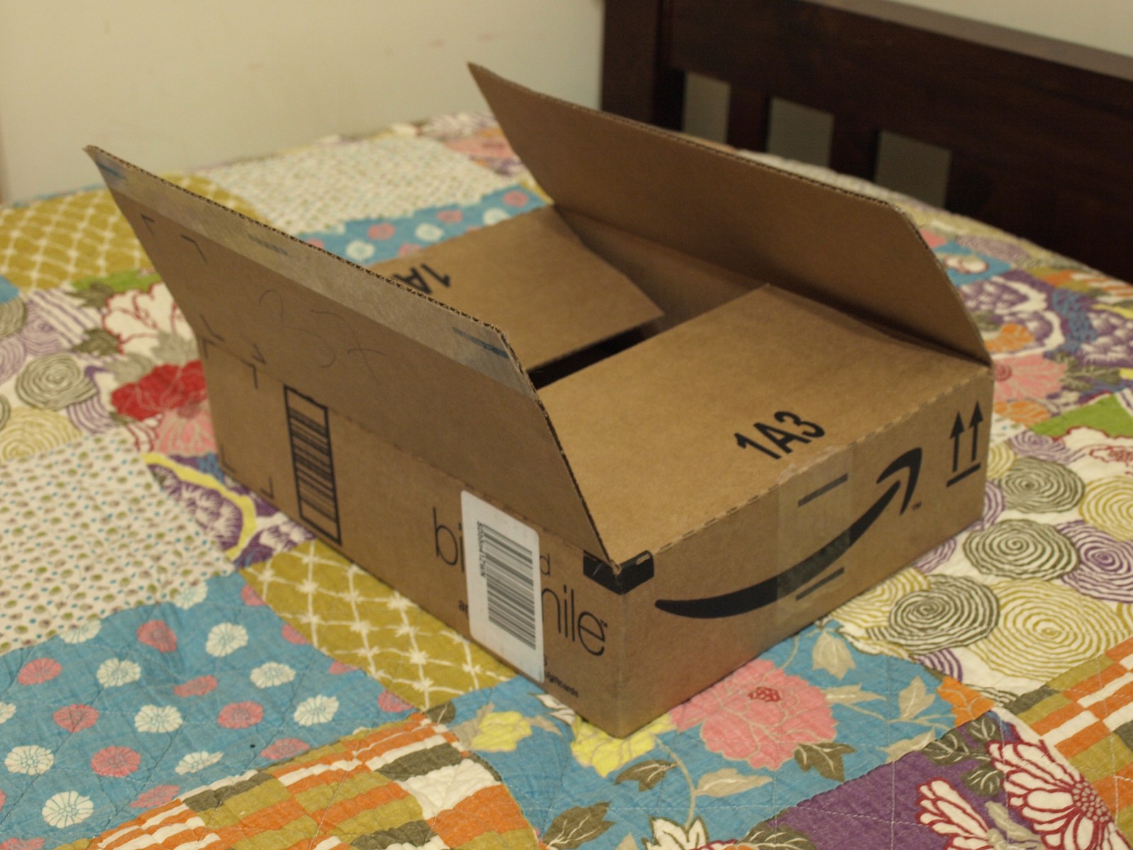 Open Amazon delivery box on a patterned tablecloth, with the Amazon smile on its side