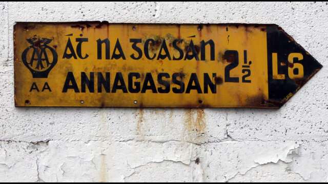 An old yellow AA fingerpost showing the Irish and English names for Annagassan with a shared right-pointing arrow.
