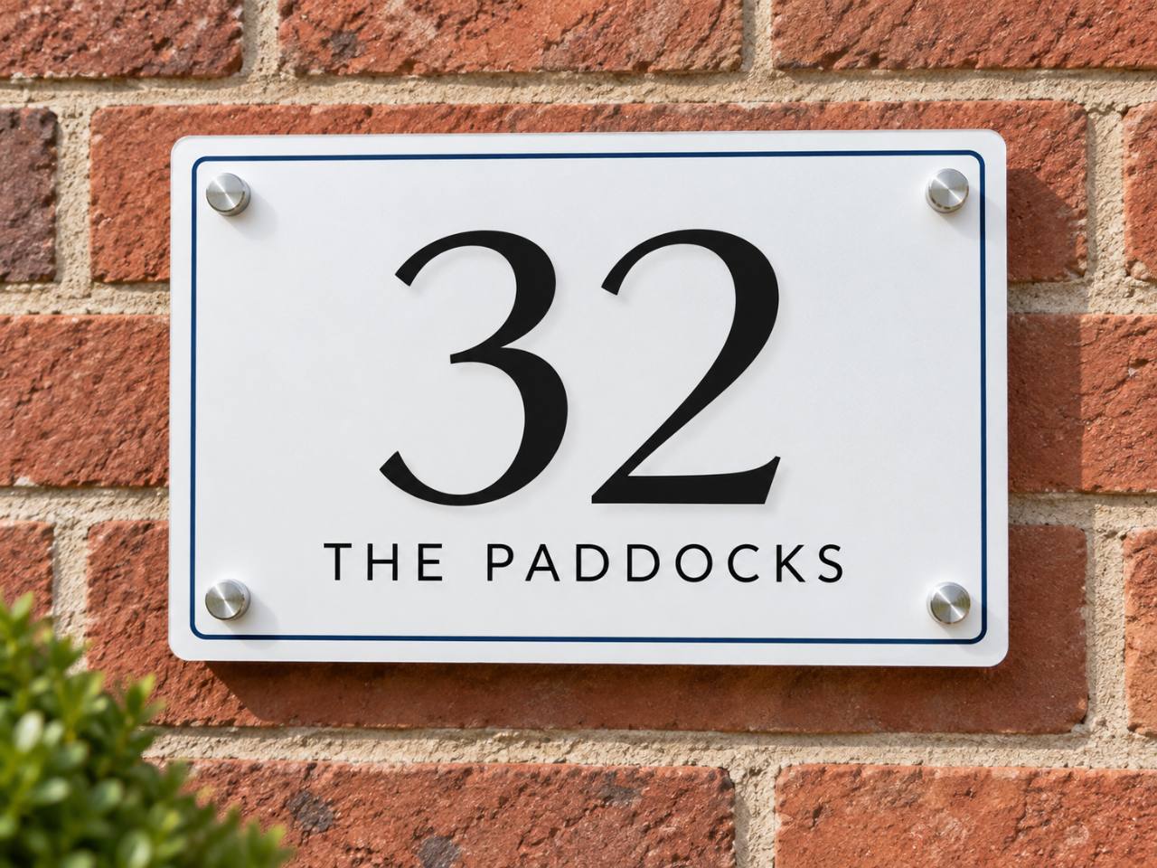 Illustrative rectangular house number and property name plaque mounted on a brick wall